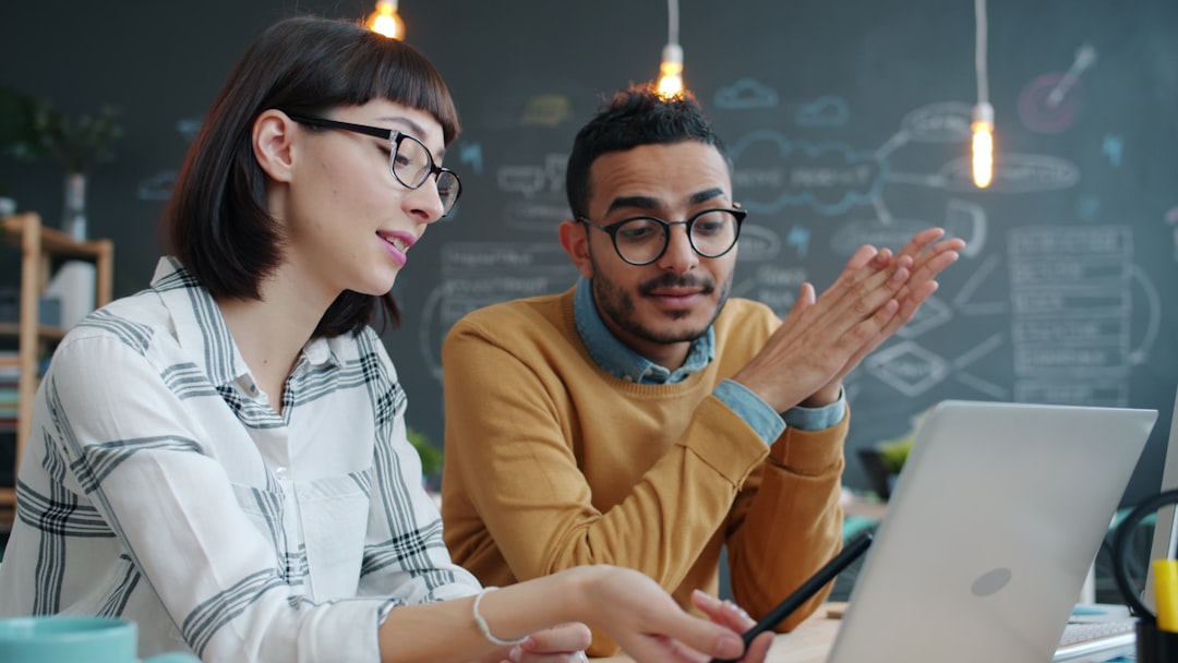 Coworkers reviewing operations on a laptop representing fully managed outsourcing, QA, coaching, and reporting