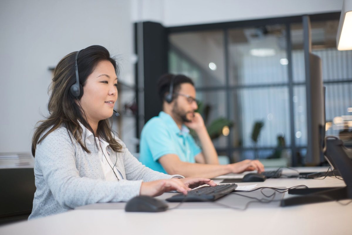 Two support agents with headsets working on computers in an office